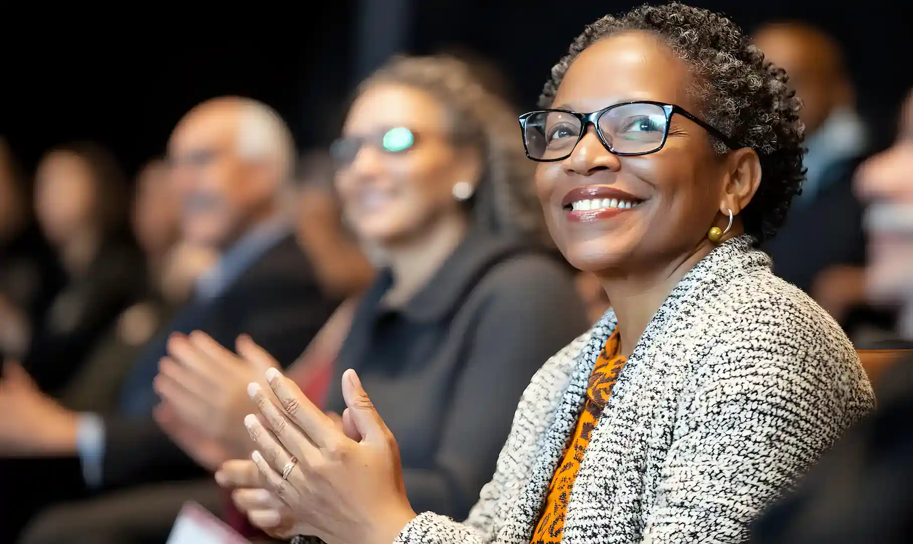 black female smiling and clapping at a seminar