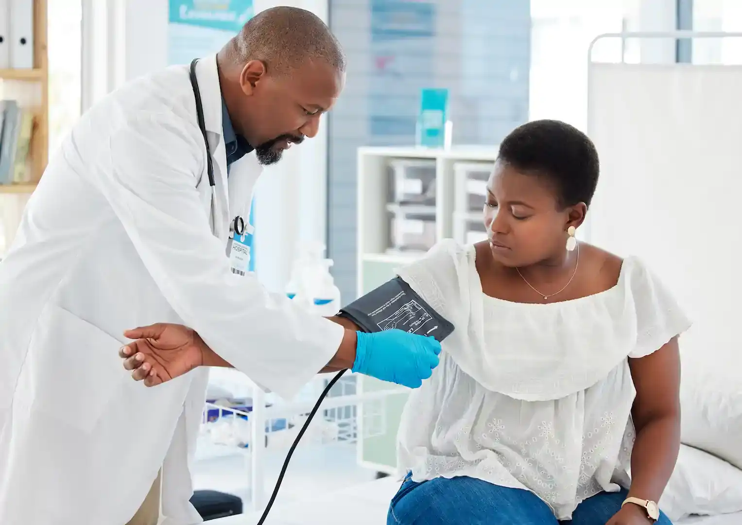 black male doctor taking blood pressure of black female